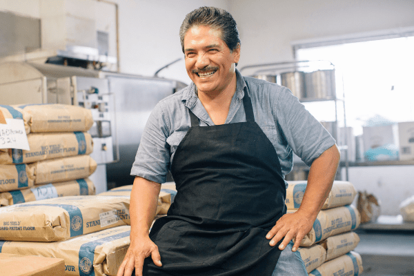 Bakery owner in his kitchen with bags of flour.